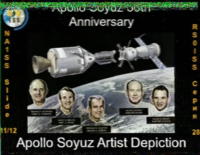SSTV image from the ISS, Slide 11 of 12, for the Apollo-Soyuz 50th Anniversary. The image shows an artist's depiction of the Apollo and Soyuz spacecraft docked together in orbit above the Earth. Below the spacecraft are portraits of the five crew members: astronauts Thomas Stafford, Vance Brand, and Deke Slayton, and cosmonauts Alexei Leonov and Valeri Kubasov. The text at the bottom reads 'Apollo Soyuz Artist Depiction'